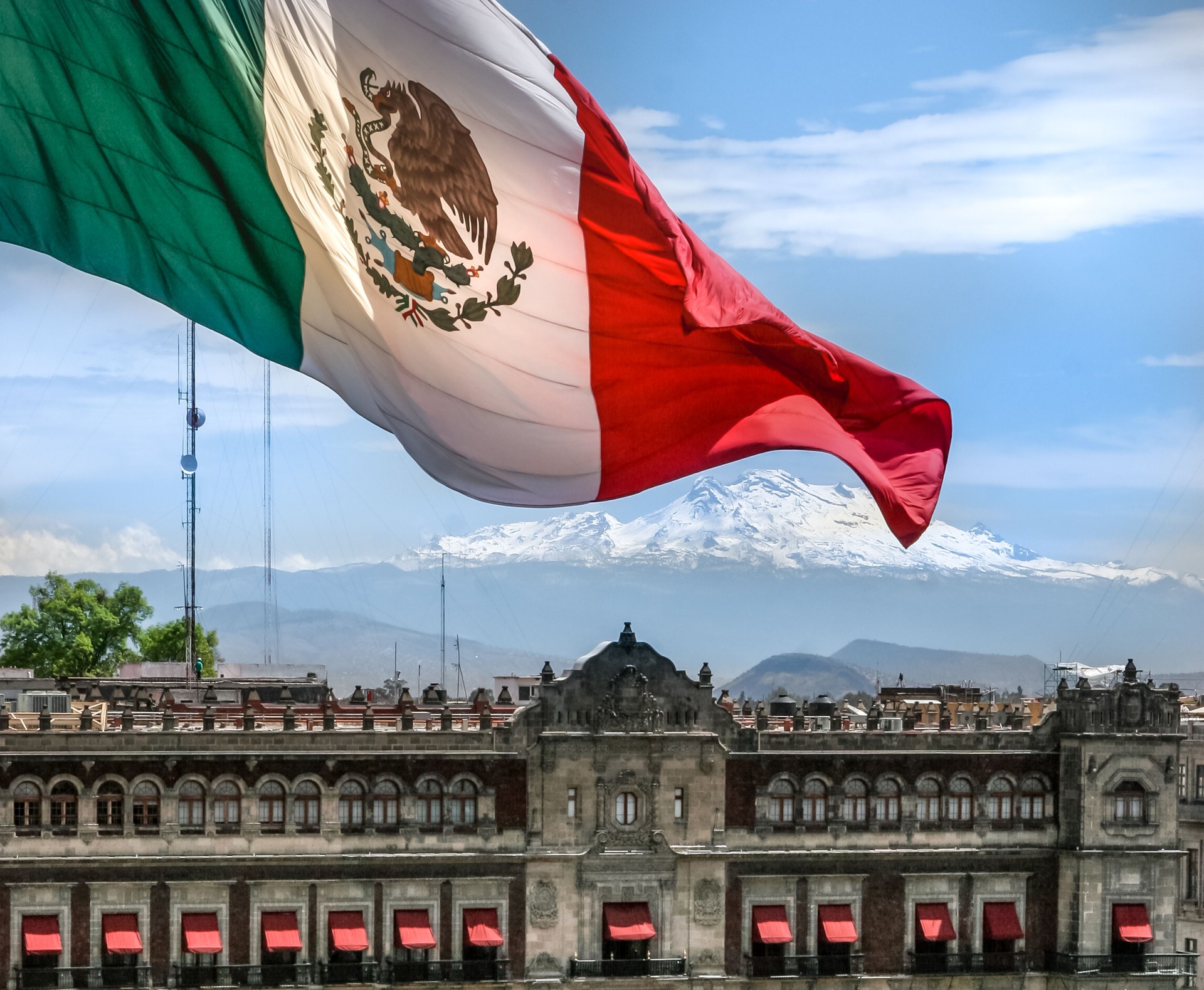 The monumental flag of Mexico flies in the heart of Mexico City with the Iztaccihuatl Volcano on the horizon