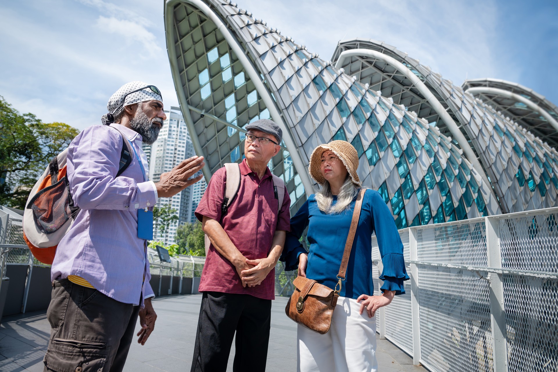 Two Asian senior tourist enjoy the Kuala Lumpur city tour and listening to a local tour guide explaining about the architecture and the history of Saloma Bridge at Kuala Lumpur City Centre